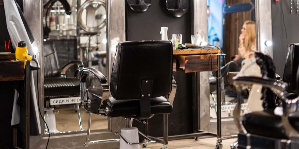 Fauteuil en cuir noir vintage de coiffeur devant un miroir