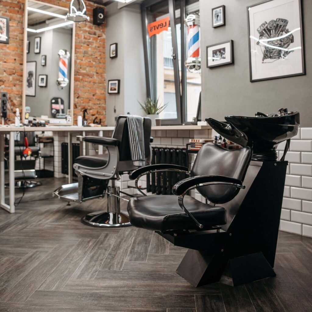 salon de barbier avec 2 fauteuils en cuir noir, miroir et accessoir de coiffure