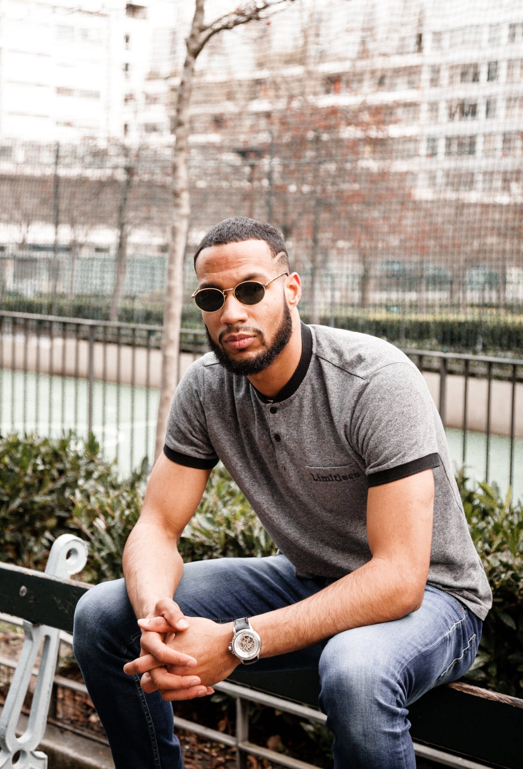 homme assis sur un banc publique avec lunette de soleil